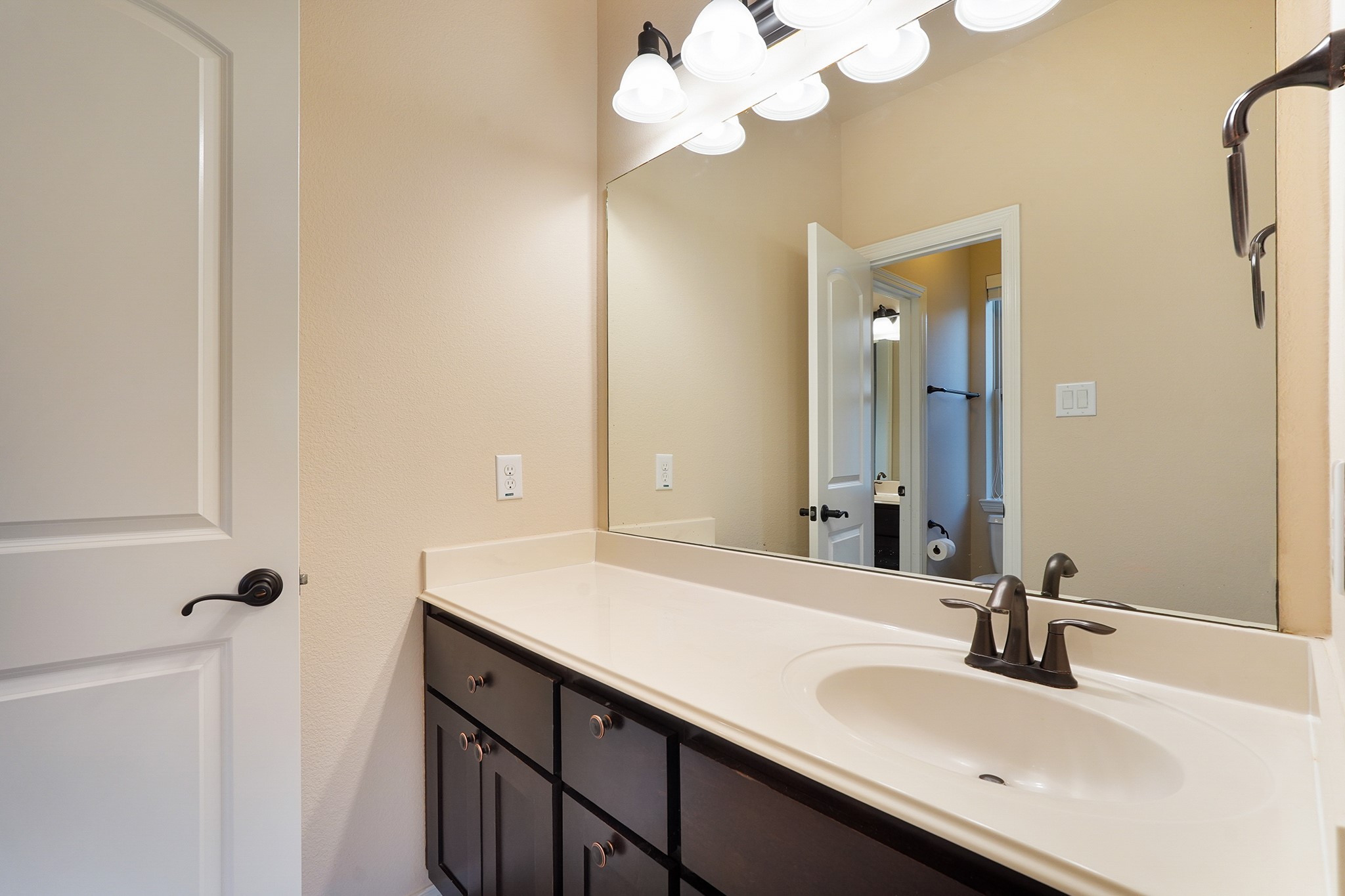 SECOND Flr-Bath#4: This bathroom features a modern, clean design with a large mirror, ample countertop space, and dark wood cabinetry. The light fixtures add brightness, and there's a stylish sink with a sleek faucet.