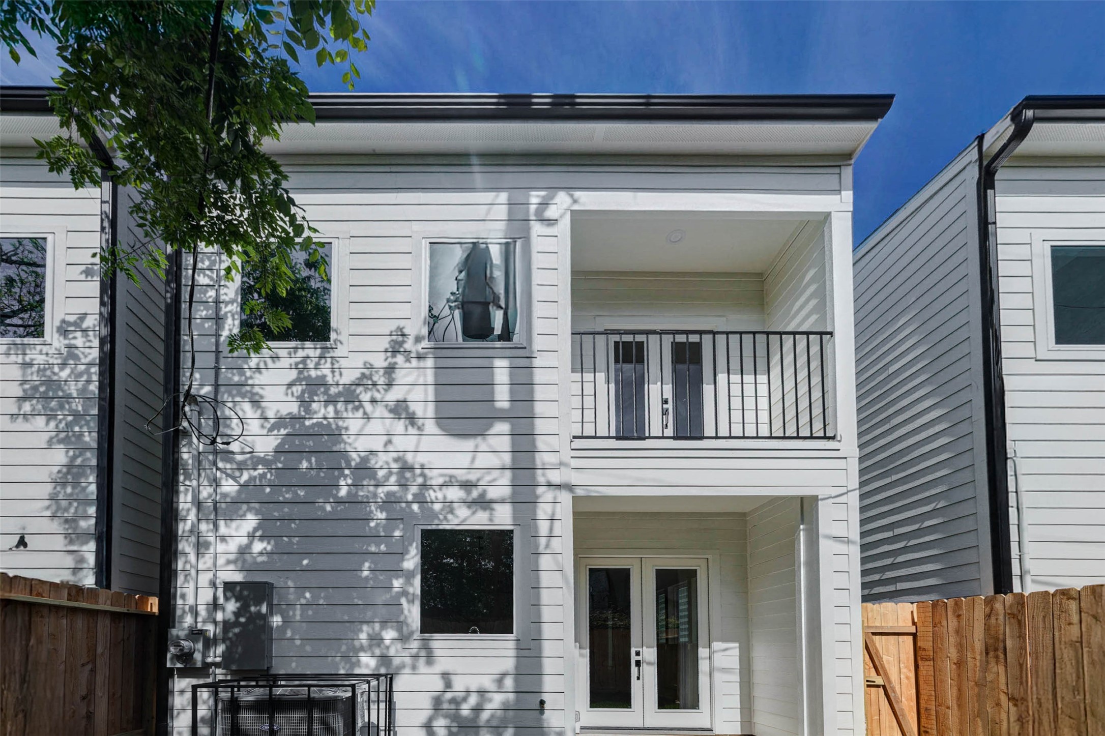 Double glass doors lead from the lower level to a covered patio, mirrored by a private balcony directly above.