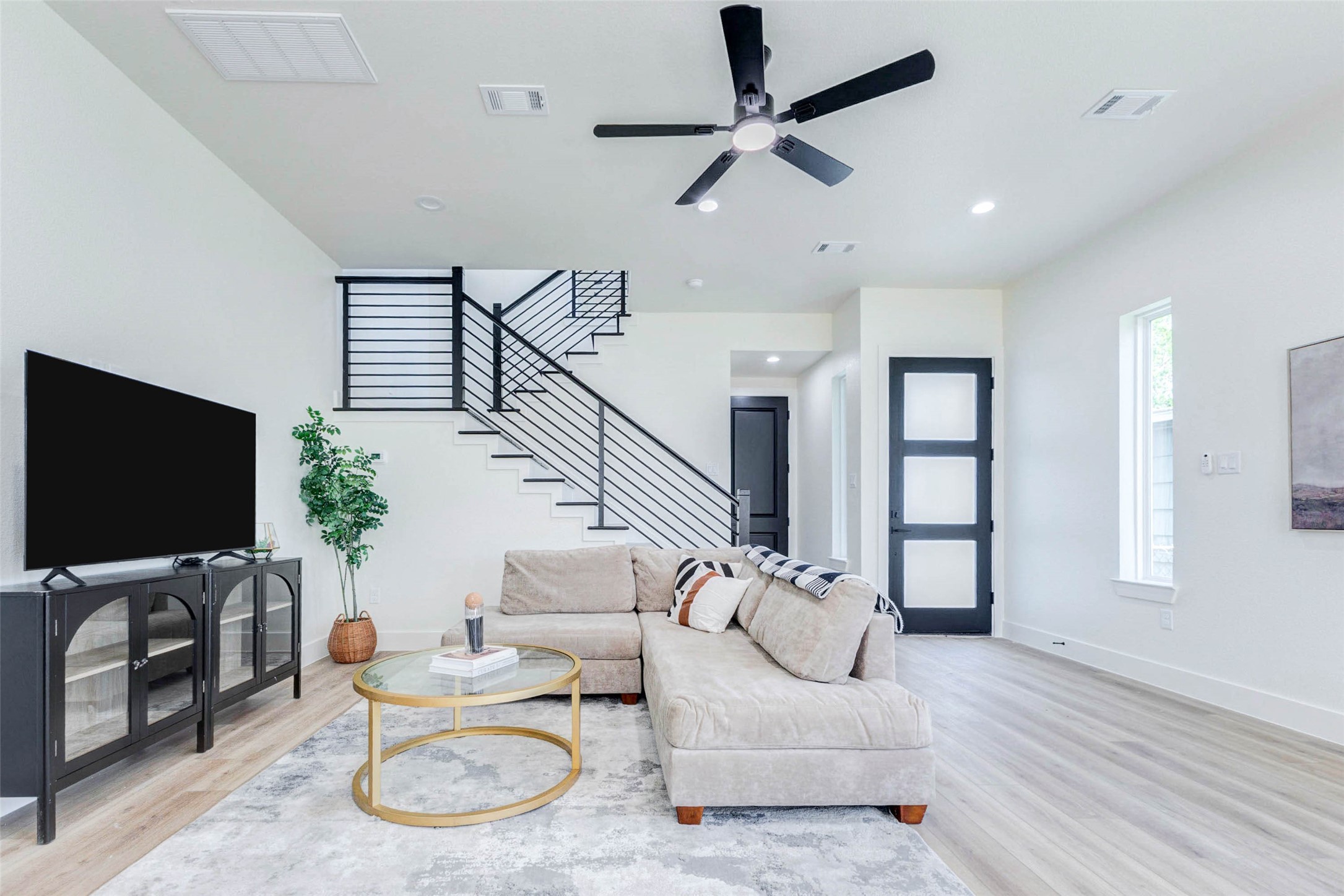 The main level features a striking modern staircase with black horizontal metal railings and a frosted-glass accent door.