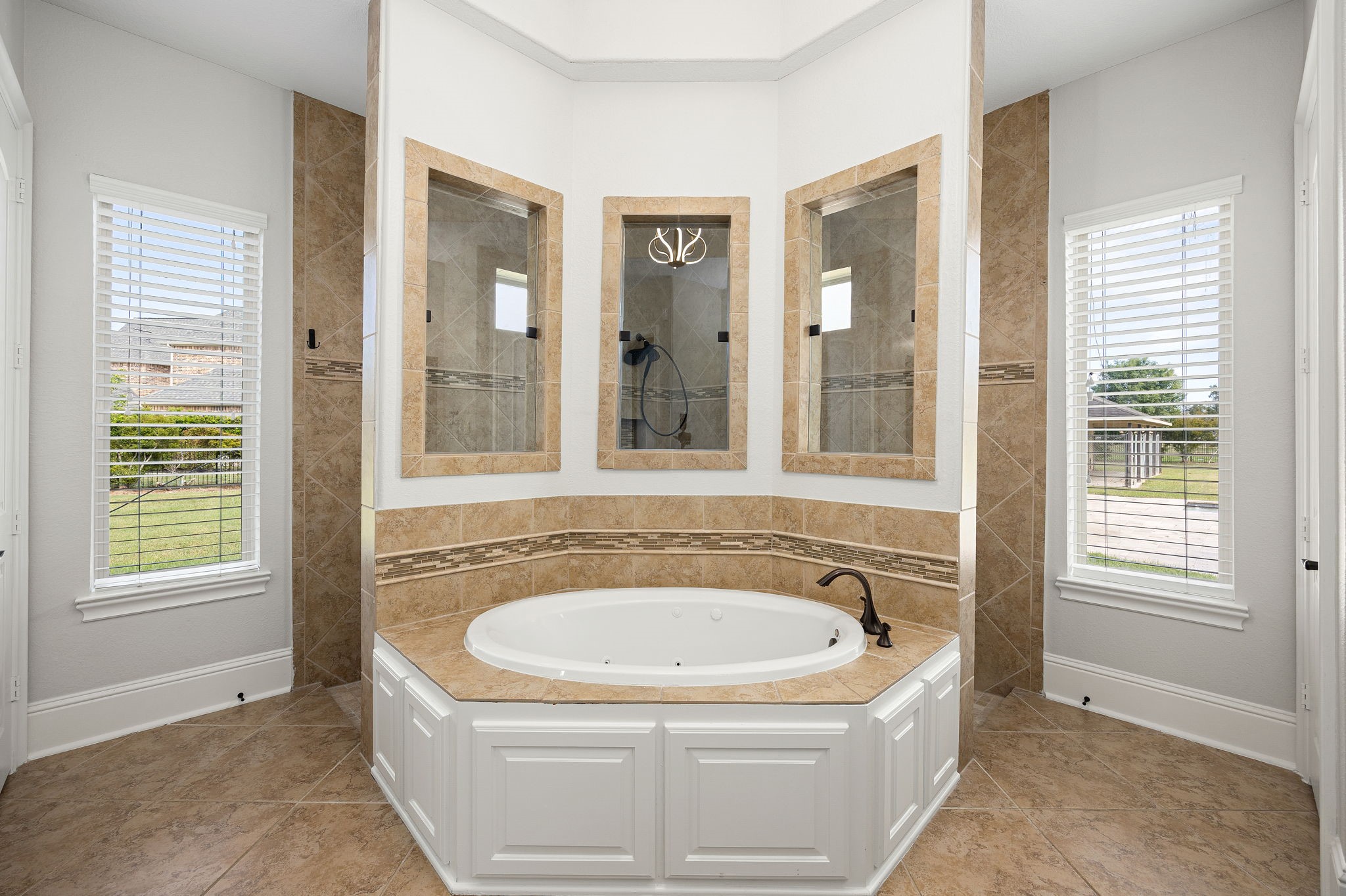The jetted soaking tub is a showpiece unto itself, enveloped in artisan tile work and bathed in natural light.