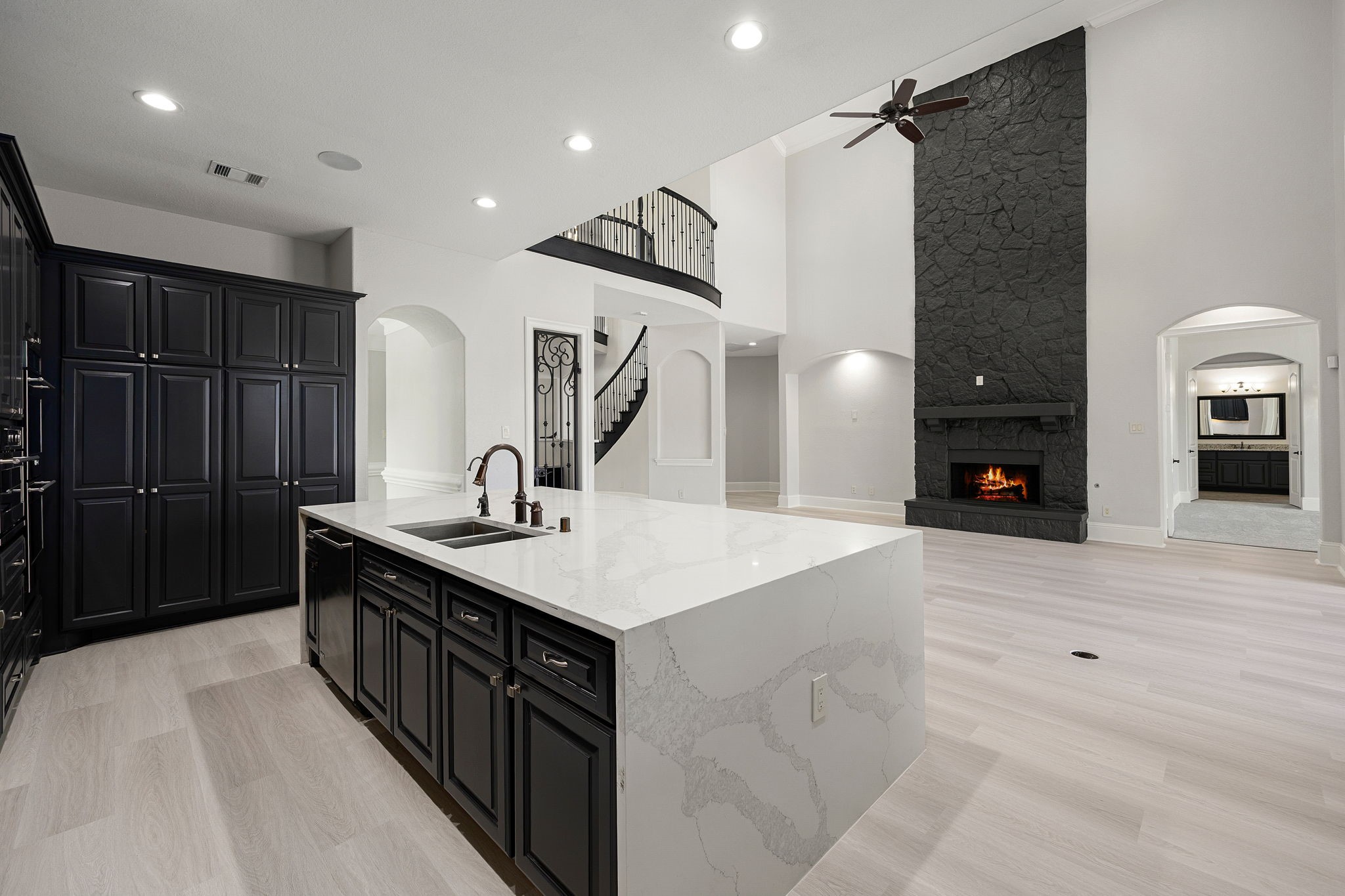 The open-concept design connects the kitchens oversized island to the living areas stone fireplace, with a staircase and overlook adding architectural interest.