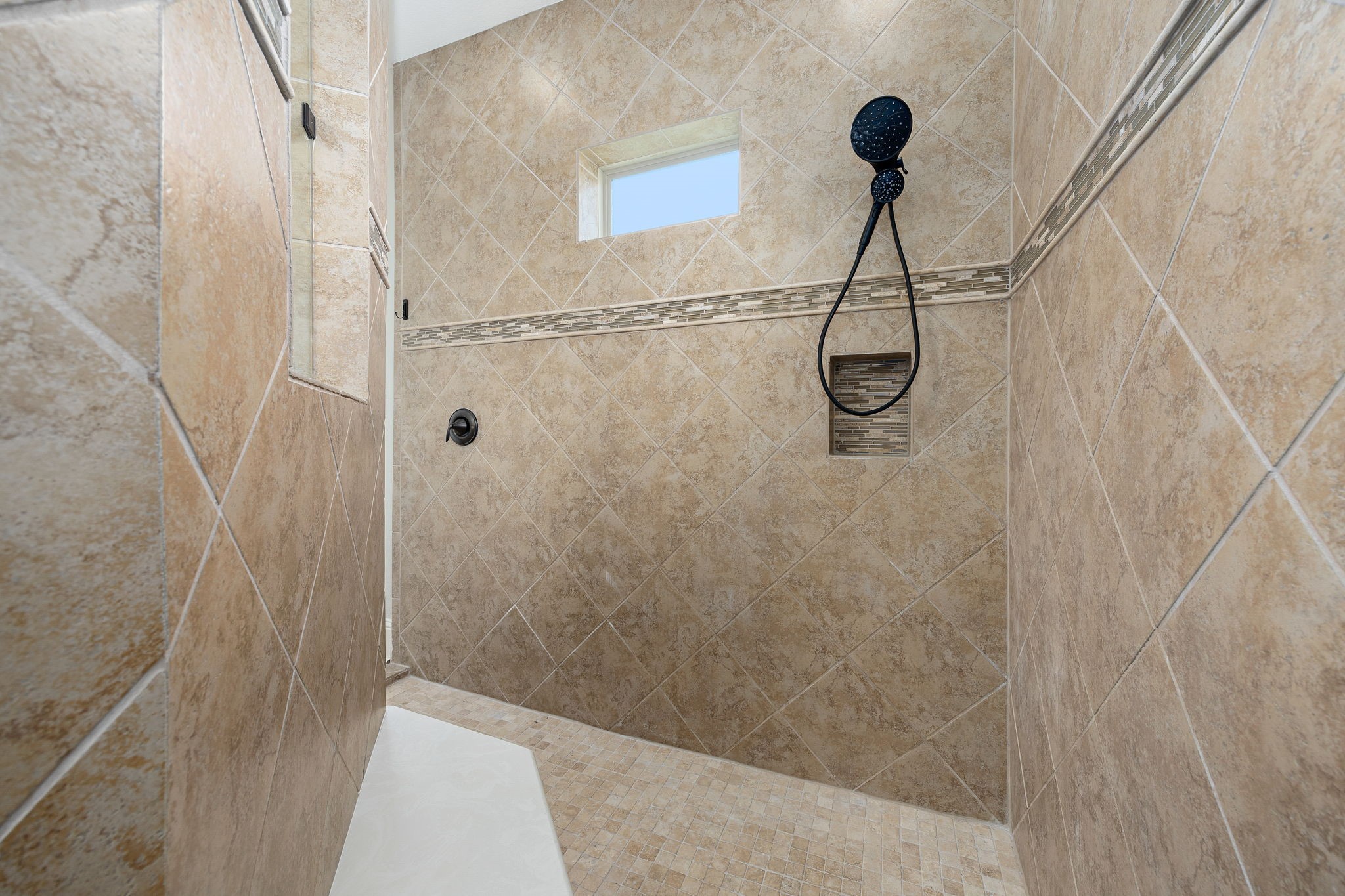 An oversized walk-in shower completes the ensuite, finished with designer tile and a built-in niche for an elevated everyday experience.