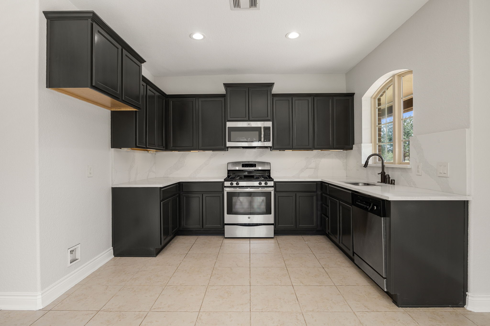 The kitchen offers sleek dark cabinetry, a stainless gas range, microwave, and dishwasher, every comfort of home in this private guest suite.
