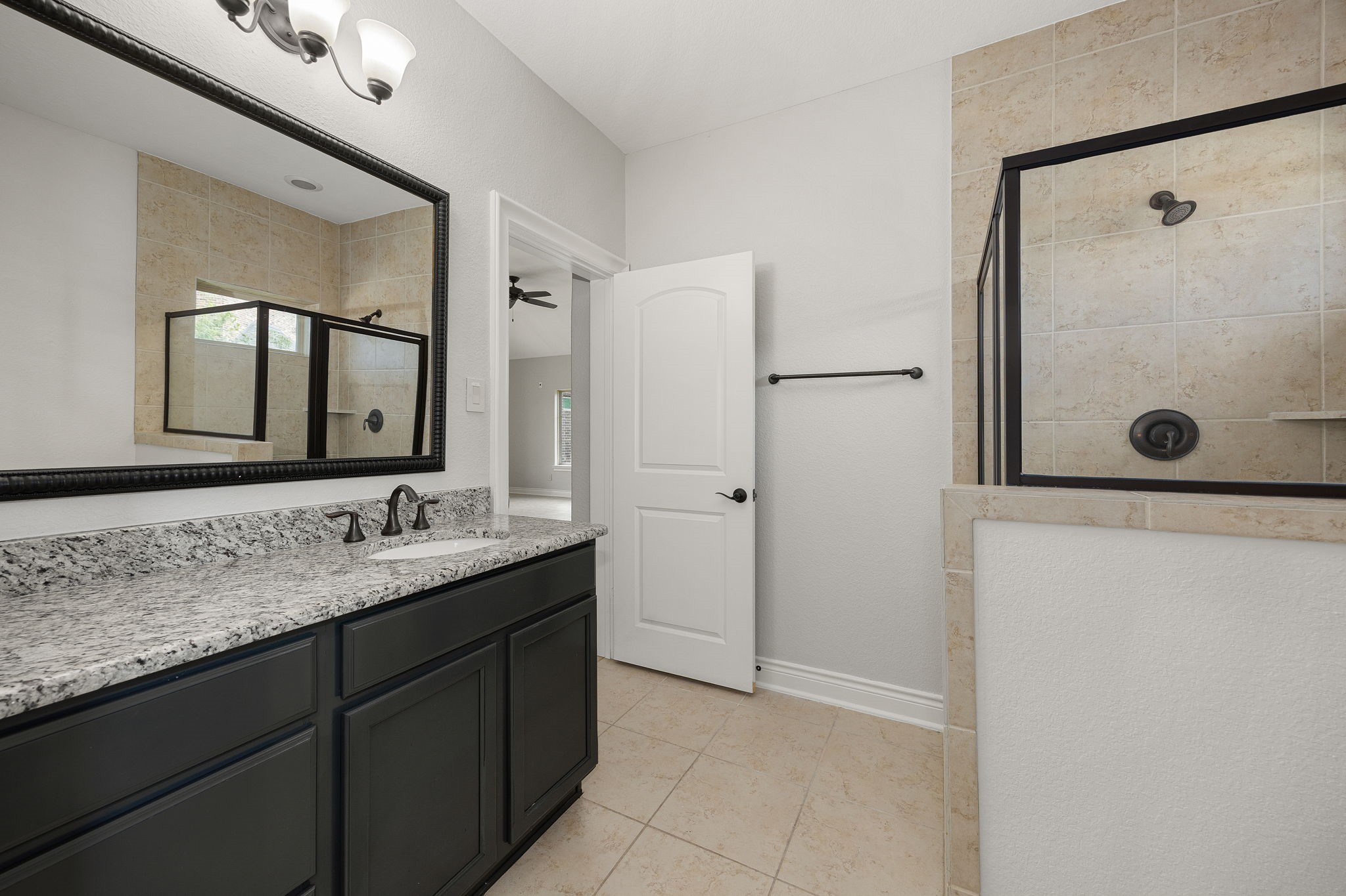 The full bathroom features a granite-top vanity and a glass-enclosed walk-in shower, offering guests a comfortable, private retreat.