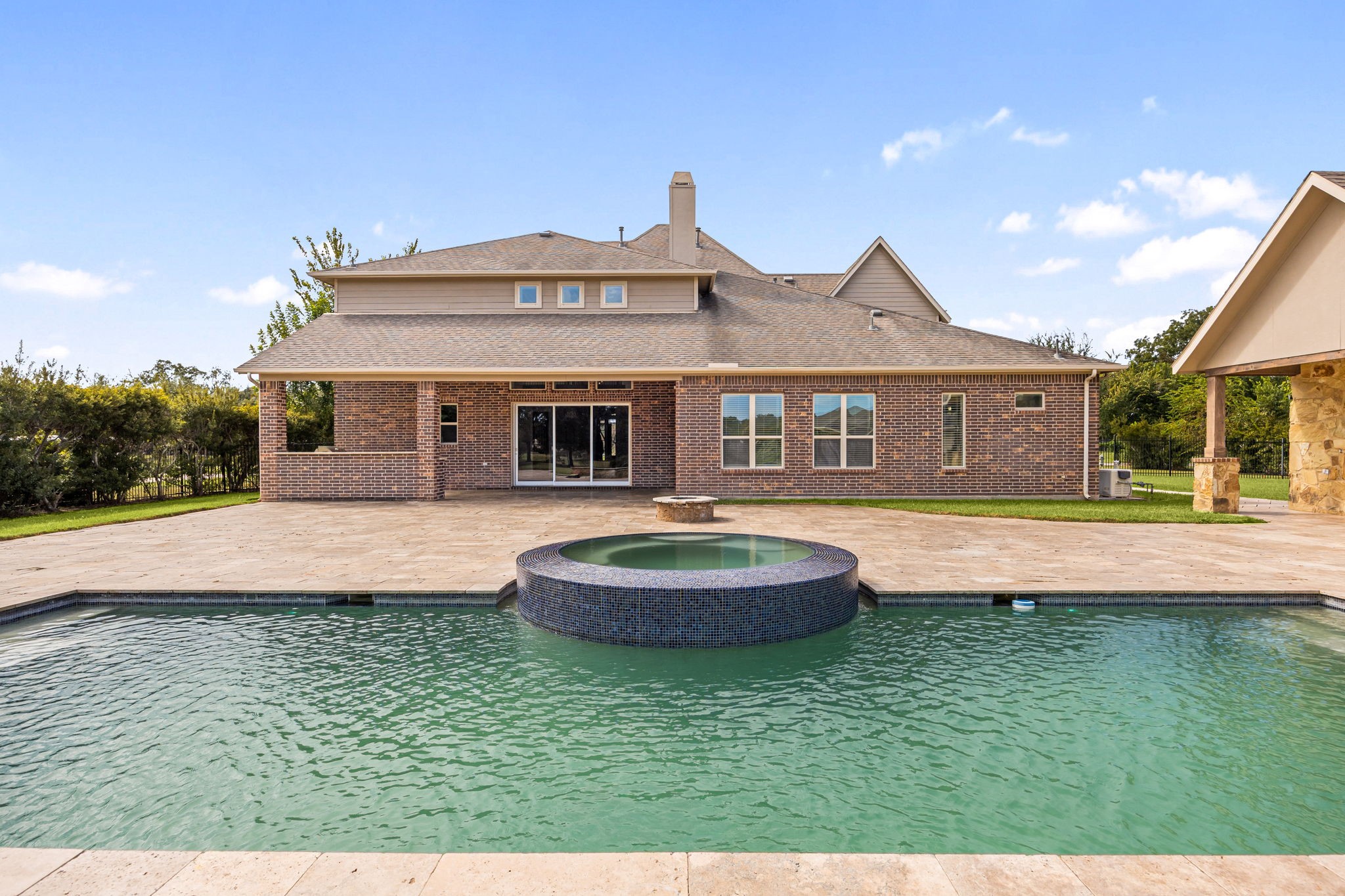 The resort-style pool and spa offer a stunning centerpiece to the backyard, framed by elegant travertine decking and lush, manicured lawn.