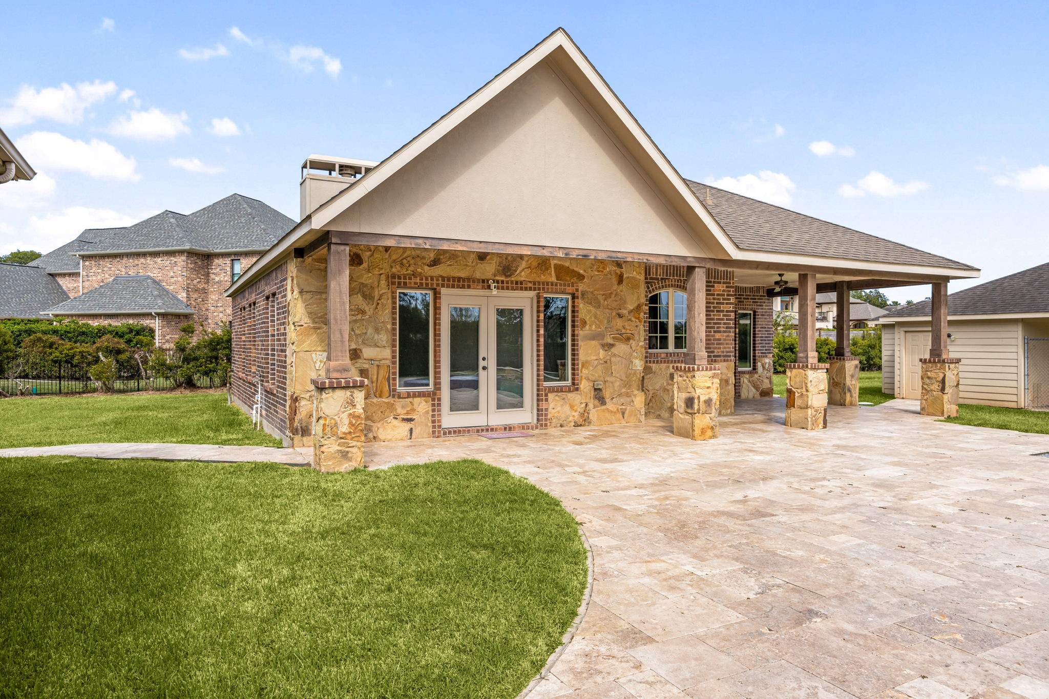 The private casita is beautifully finished with stone and brick accents, a gabled roofline, and a covered patio with French doors, a true retreat of its own.