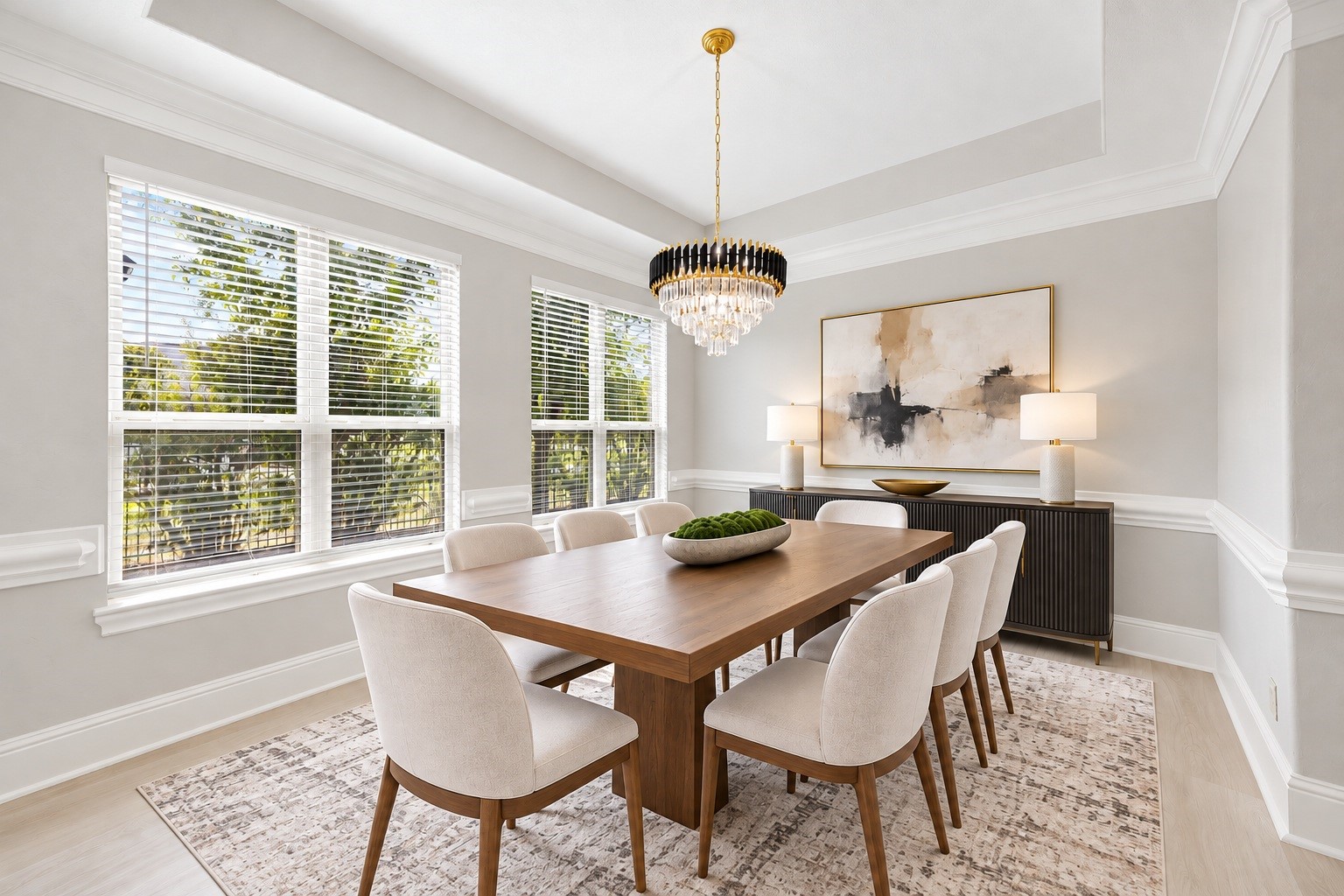 A formal dining area is framed by large windows, a tray ceiling, and an elegant chandelier, offering a bright and sophisticated space for entertaining. Virtually staged.