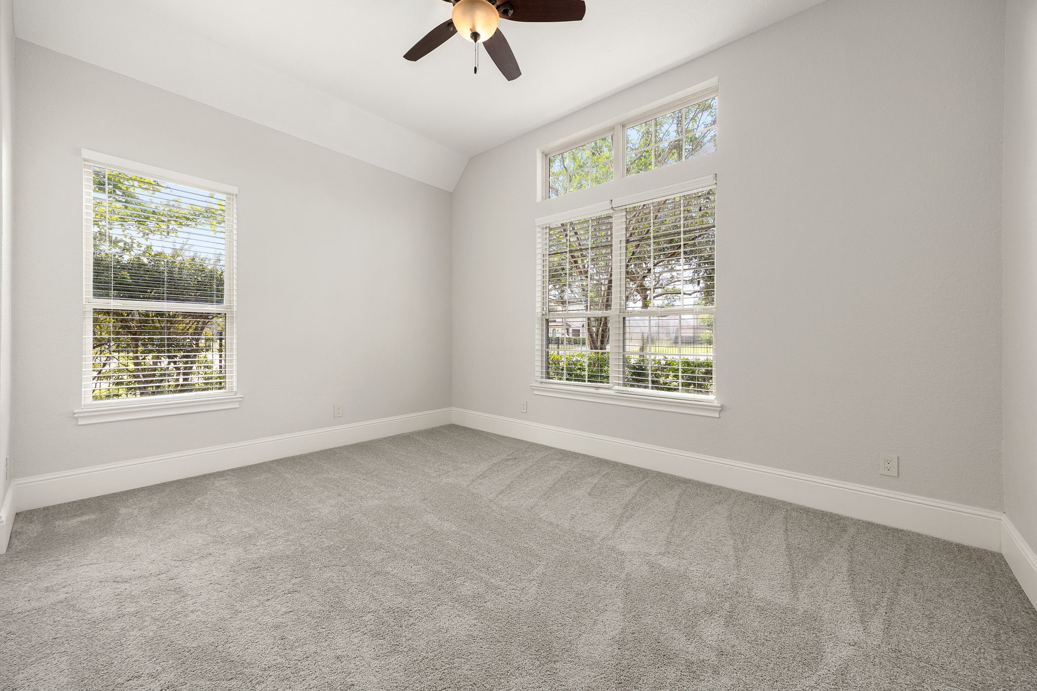 A beautifully appointed secondary bedroom downstairs offers soaring vaulted ceilings and abundant natural light through oversized windows.
