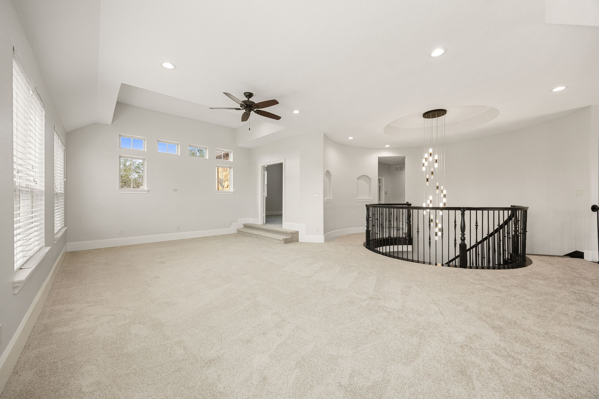 A striking curved staircase and statement chandelier anchor this second level of the gameroom, adding architectural elegance to this impressive entertaining space.