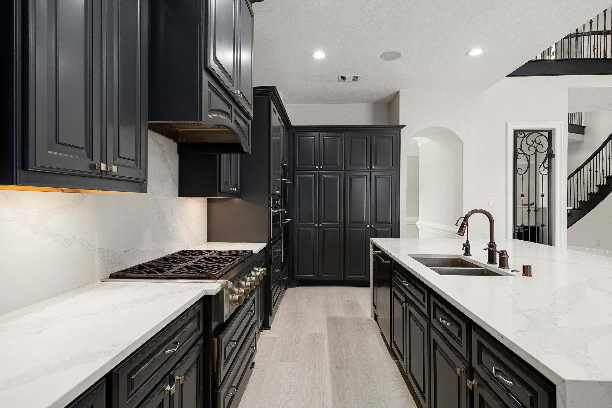A gas cooktop with a statement vent hood anchors the space, surrounded by an abundance of cabinetry and under-cabinet lighting for both style and function.