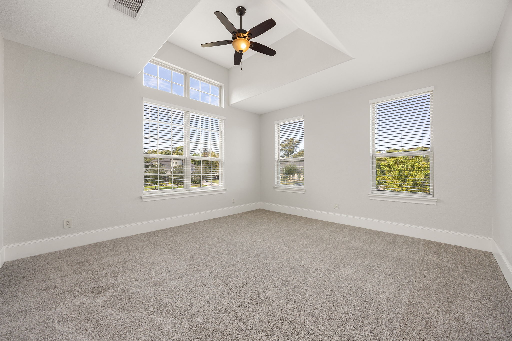 The fourth bedroom impresses with a ceiling fan and oversized windows that frame picturesque views of the community.