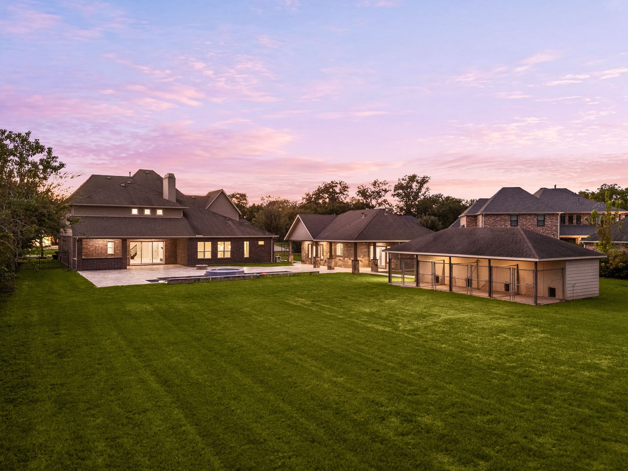This elevated view captures the full scope of the property at twilight, the main residence, casita, pool, and grounds all beautifully illuminated.
