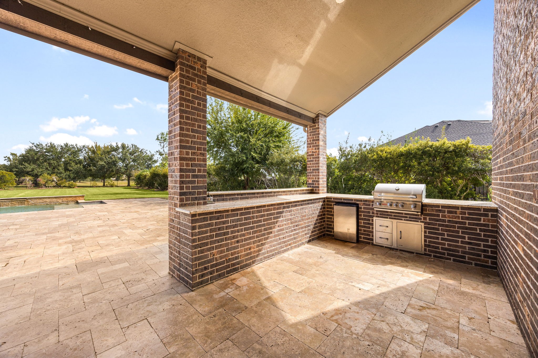 A fully equipped outdoor kitchen, complete with a built-in grill, mini fridge, and granite countertops, makes al fresco entertaining effortless under the covered patio.