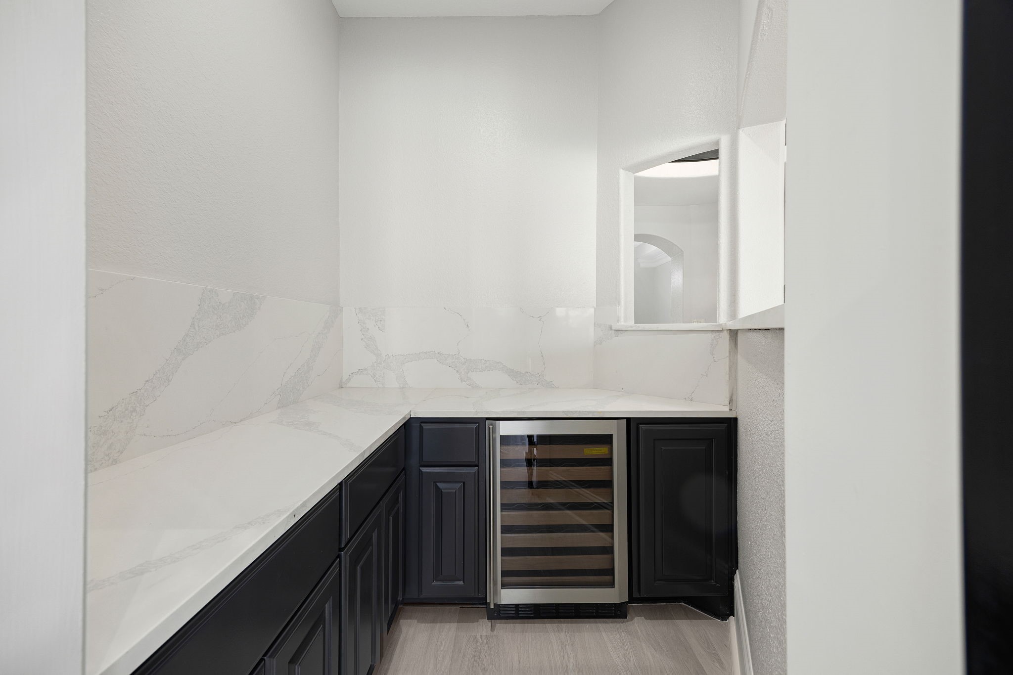 A butlers pantry with a built-in wine fridge and marble-look countertops adds convenience and style, perfect for hosting.