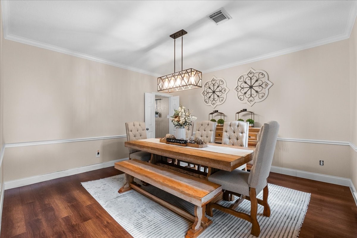 Elegant dining room featuring a rustic wooden table with bench seating, plush upholstered chairs, and a stylish chandelier, set against warm-toned walls and chic decor accents.