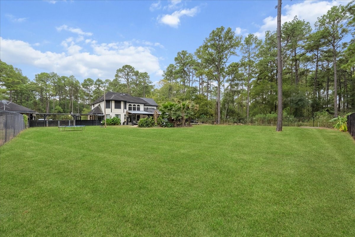 Expansive backyard with lush green lawn, surrounded by mature trees, offering privacy and a picturesque view of the two-story home.