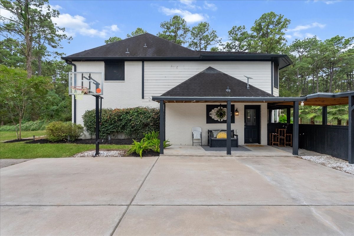 Charming two-story home with a welcoming covered patio, nestled amidst lush greenery. The spacious driveway and basketball hoop add a touch of leisure to this serene property.