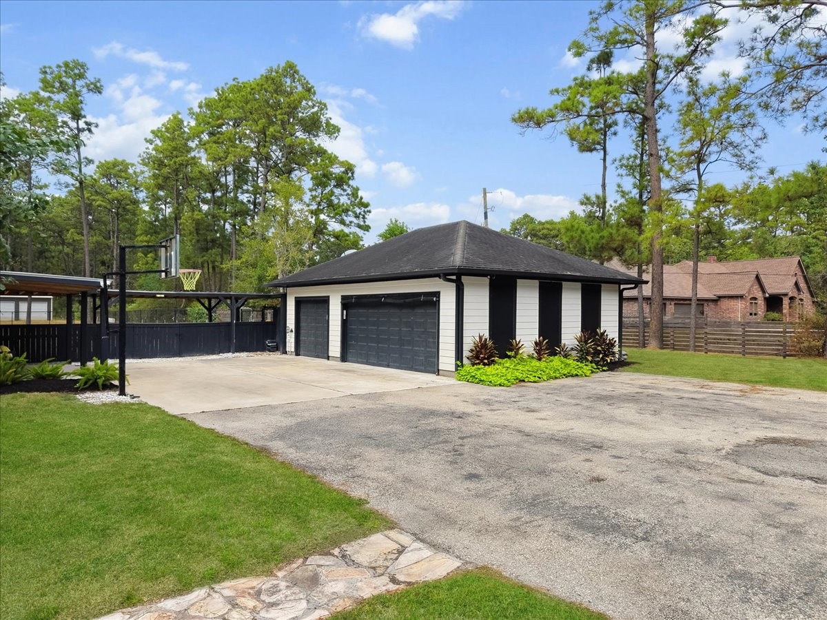 Spacious driveway leads to a modern three-car garage, surrounded by lush greenery and tall trees, offering ample parking and privacy. Garage is also engineered to ad upstairs garage apartment.