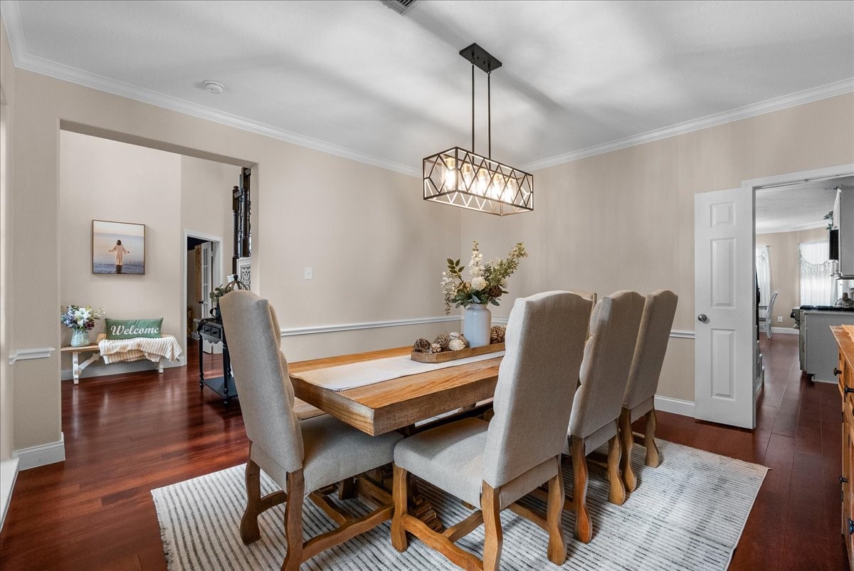 Elegant dining room with a stylish chandelier, rich wood like flooring, and a spacious table perfect for gatherings.