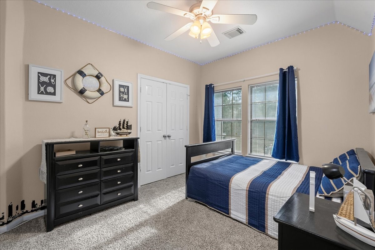 Charming bedroom with nautical decor features a cozy bed, ample natural light from large windows, and a spacious closet, creating a relaxing retreat.