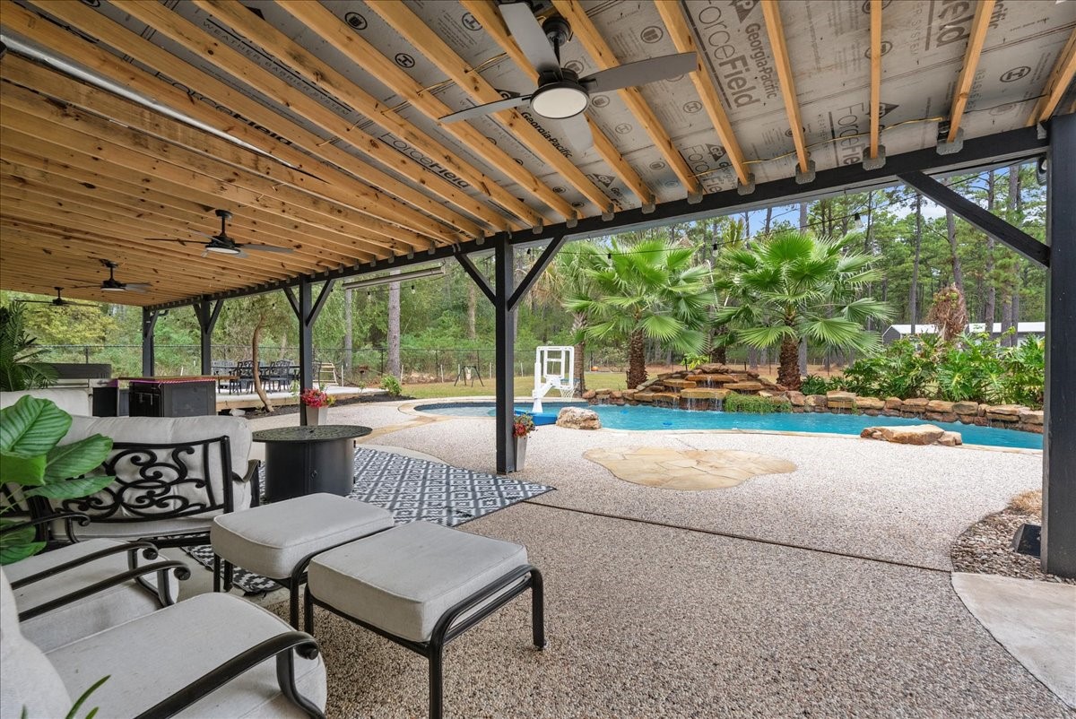 Experience outdoor living at its finest with this stunning covered patio, featuring elegant seating, ceiling fans, and a view of the sparkling pool and lush landscaping.