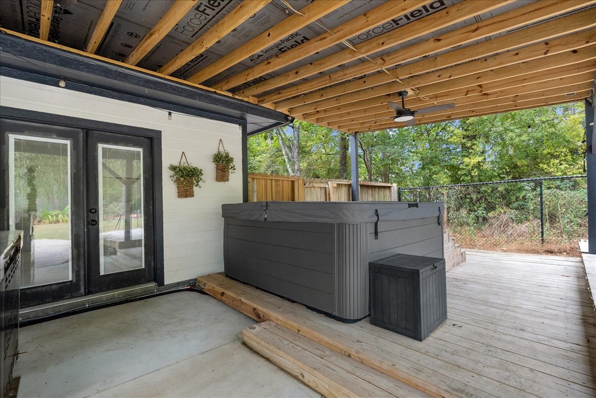Enjoy a covered outdoor retreat featuring a spacious hot tub, perfect for relaxation and entertainment, with easy access through elegant French doors.