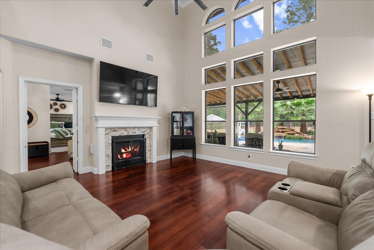 Elegant living room featuring soaring ceilings, a cozy fireplace, and expansive windows overlooking a scenic backyard oasis.