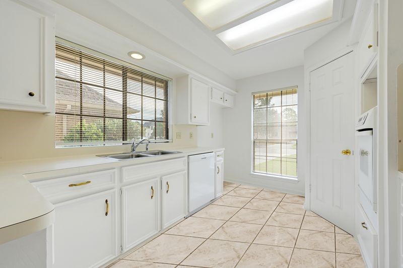 Bright, airy kitchen with sleek white cabinetry, modern appliances, and large windows for ample natural light.