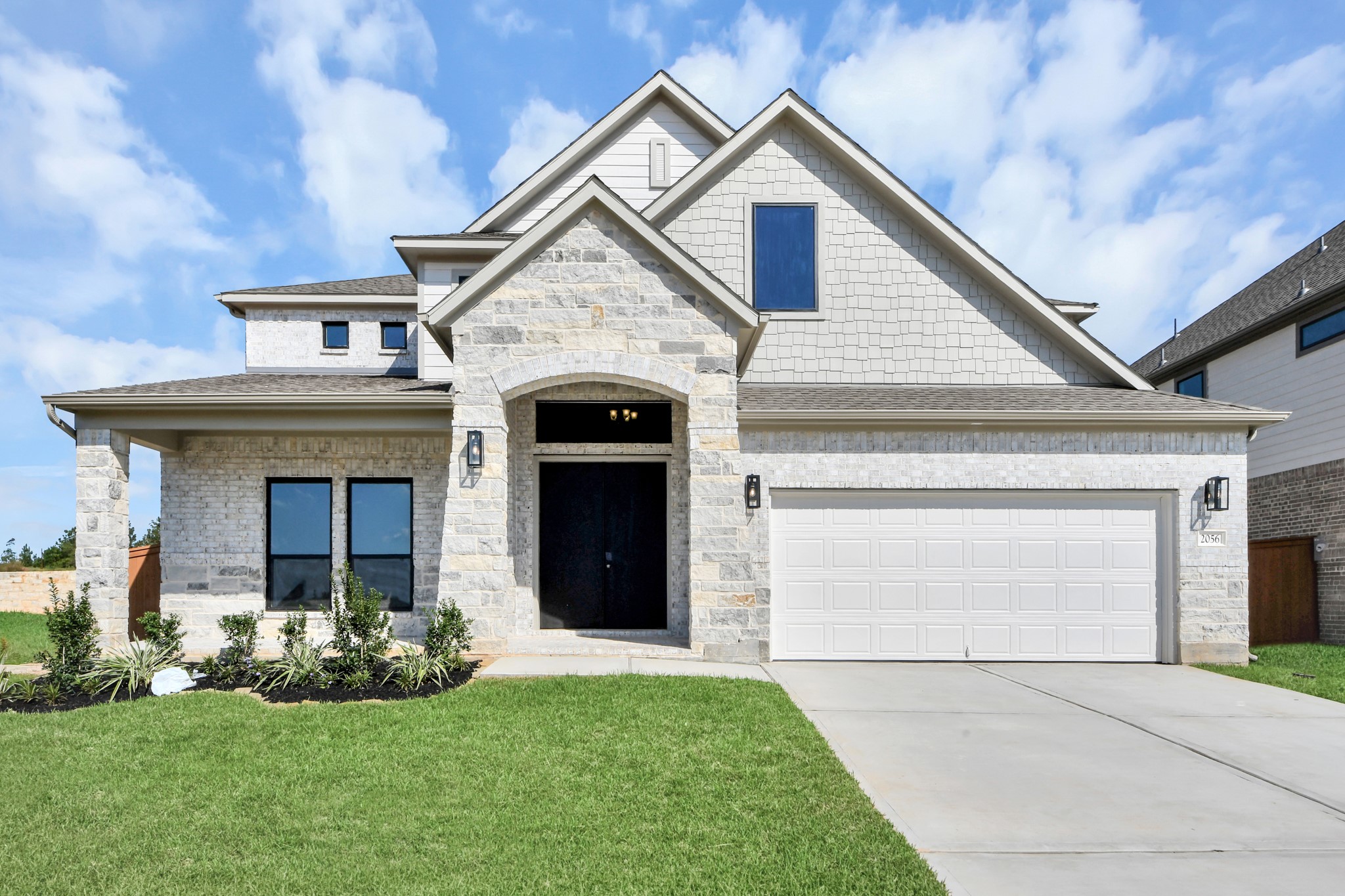 Meticulously maintained yard and lush landscape, paired with a premium elevation featuring captivating brick accents. Modern coach lights add a touch of contemporary elegance to the exterior.