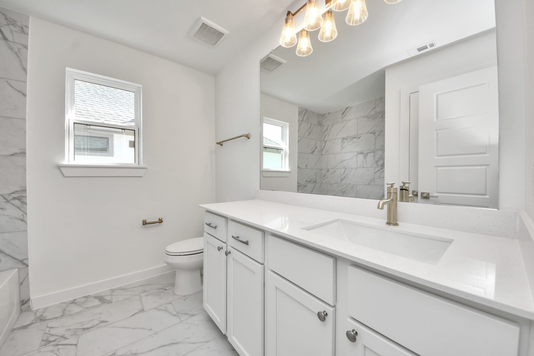 Secondary bath features tile flooring, bath/shower combo with tile surround, light stained wood cabinets, beautiful light countertop.