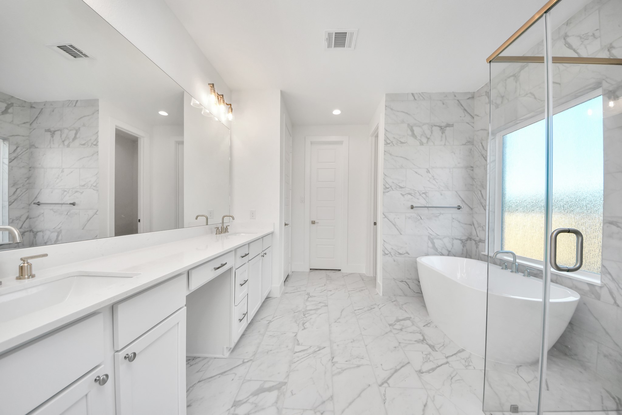 Escape to a spa-like oasis in this primary bathroom. Enjoy a walk-in shower with tile surround, a separate garden tub with custom detailing, and an elegant vanity featuring light countertops, modern hardware, and beautiful vanity lights. Experience luxury and relaxation in every detail.