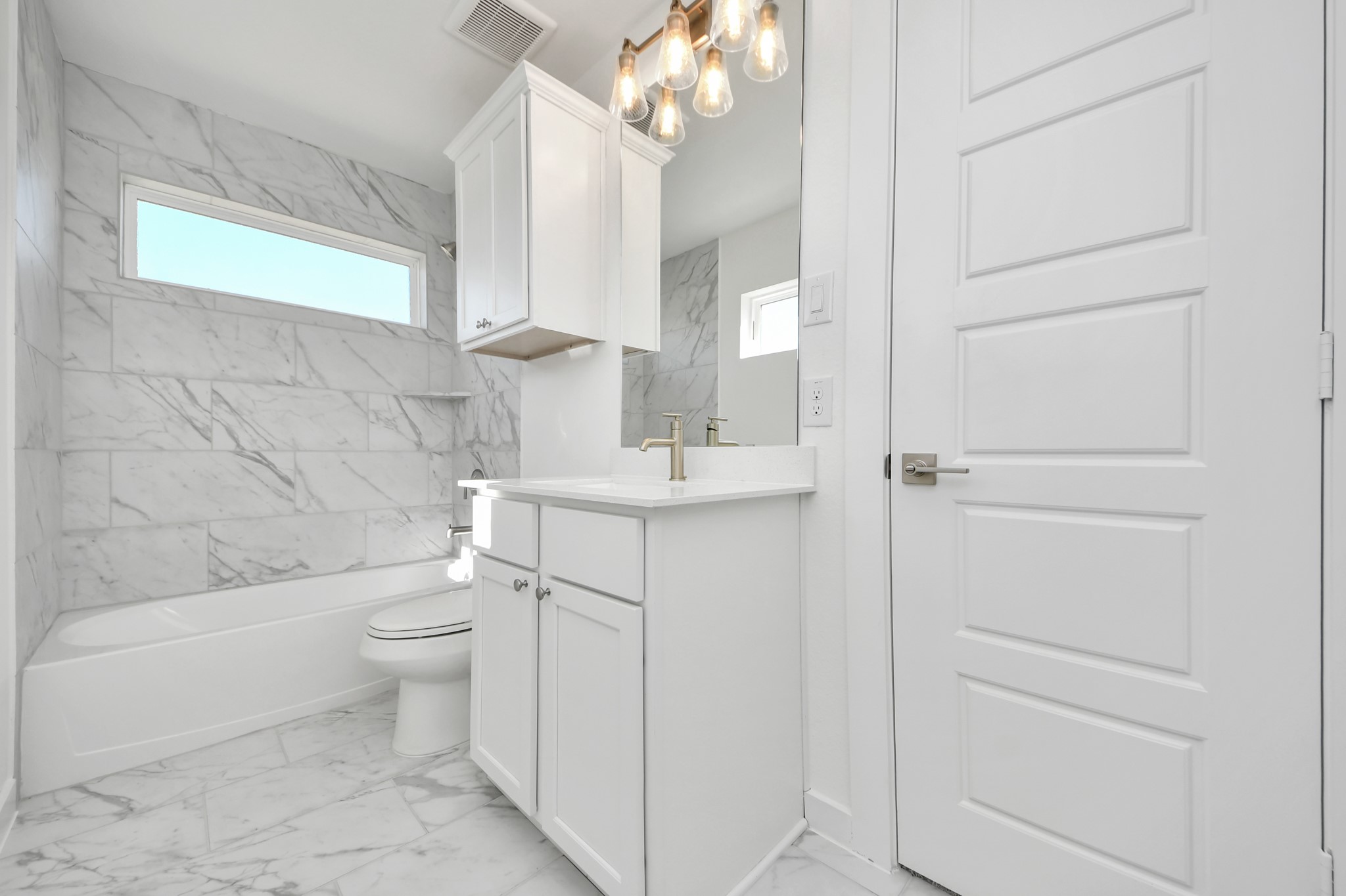 Secondary bath features tile flooring, bath/shower combo with tile surround, light stained wood cabinets, beautiful light countertop.