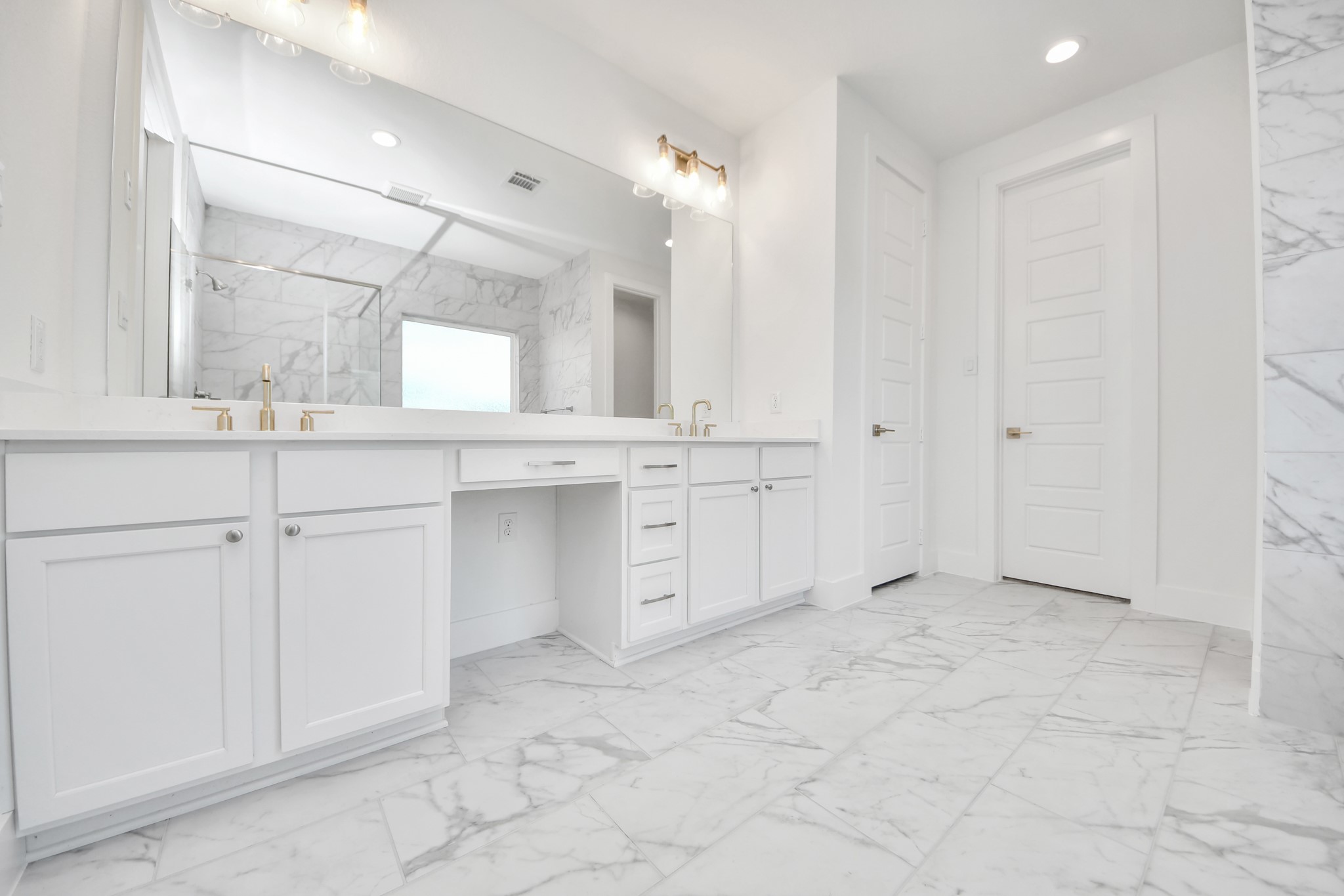 Elevate your daily routine at the elegant vanity, now equipped with double sinks, light countertops, modern hardware, and beautiful vanity lights.