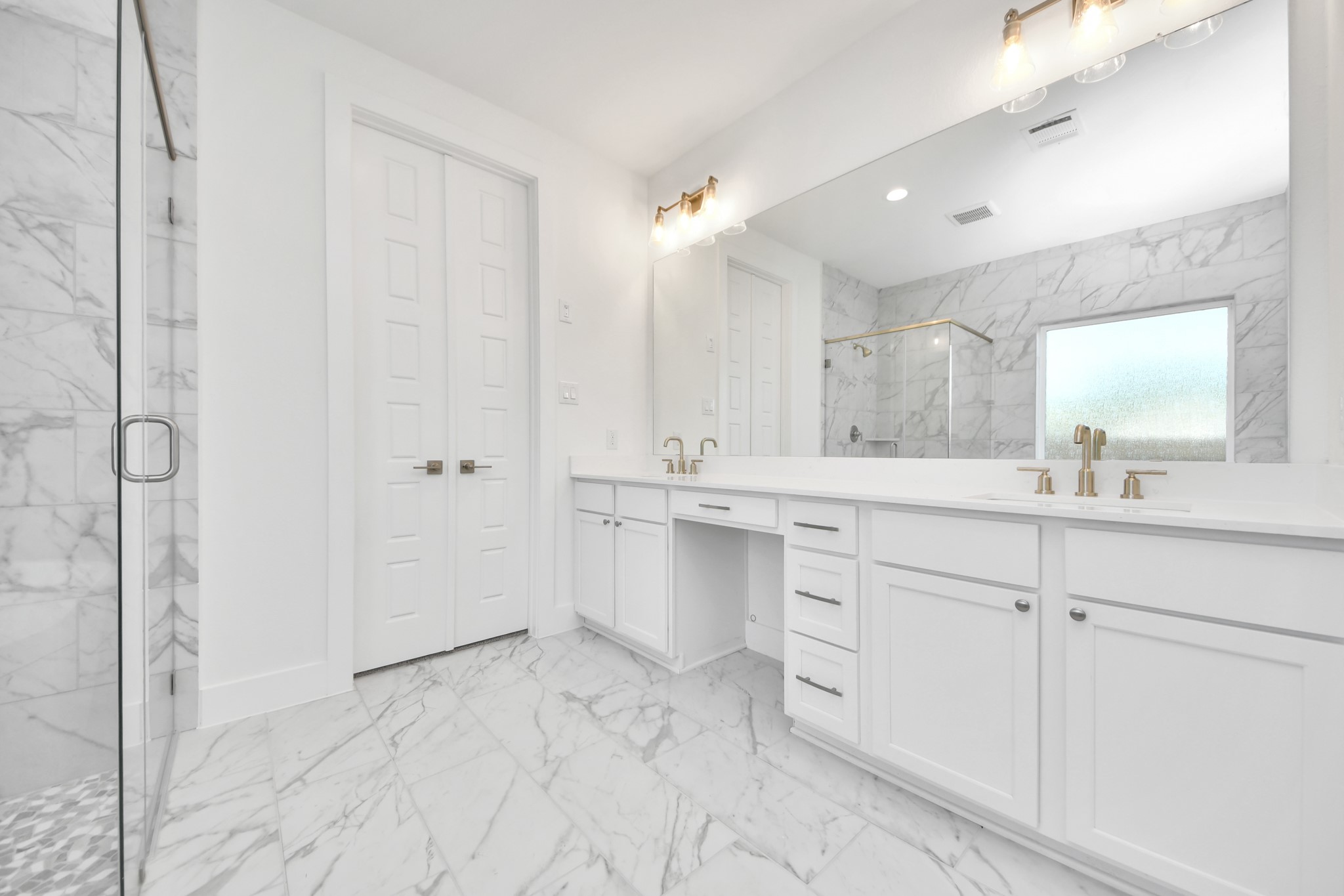 Elevate your daily routine at the elegant vanity, now equipped with double sinks, light countertops, modern hardware, and beautiful vanity lights.