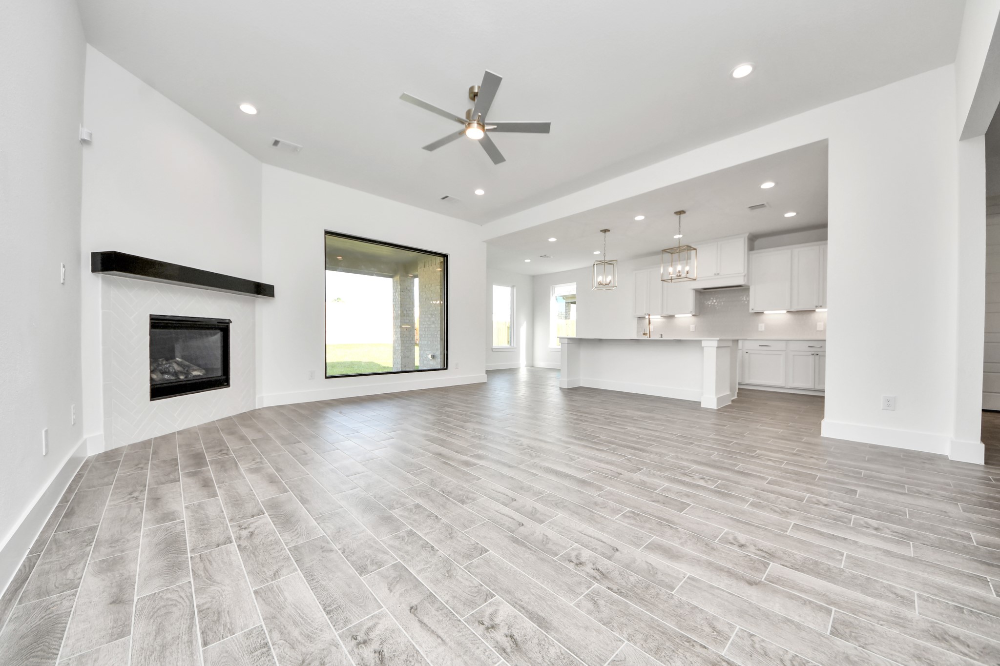 Welcome family and guests to your charming living room! With its high ceilings, recessed lighting, ceiling fan, custom paint, beautiful flooring, and large windows that let in abundant natural light, this room is perfect for gatherings.