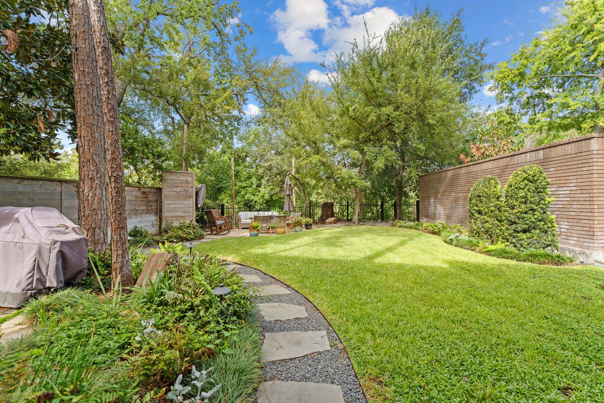 A curved stone path leads through landscaped beds to a garden patio. The fenced yard includes approximately 1,890 sq. ft. of adjoining Harris County-owned land that you get to use- but don't pay for!