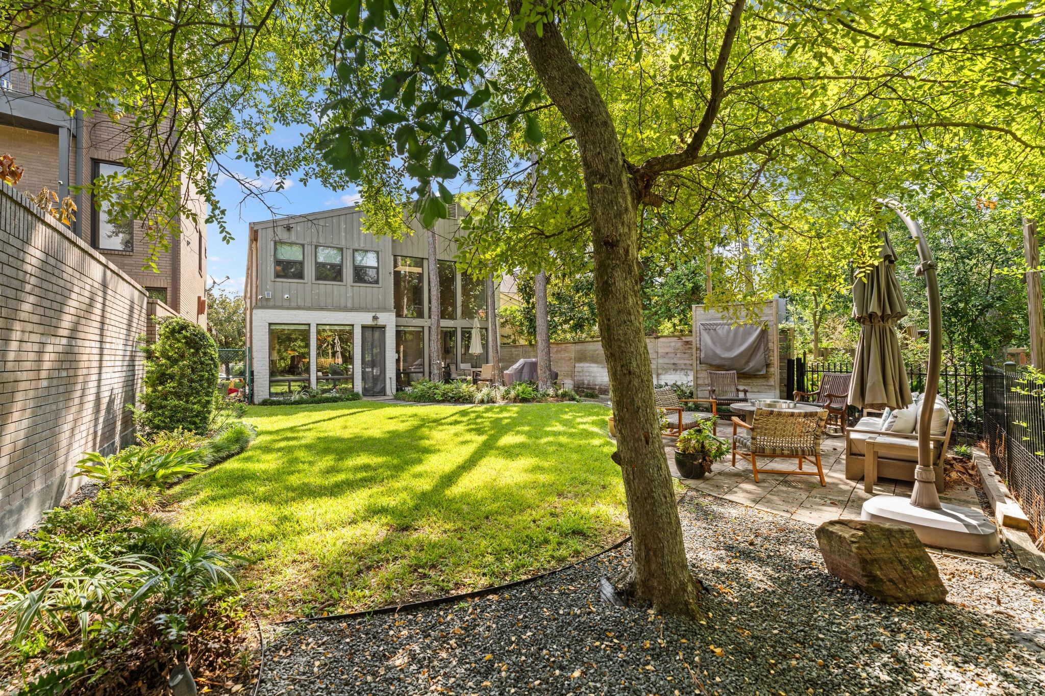 Shade trees, a lush lawn and a sitting patio create an inviting outdoor setting. The fenced yard includes approximately 1,890 sq. ft. of adjoining Harris County-owned land outside the deeded lot; buyer to verify continued use.