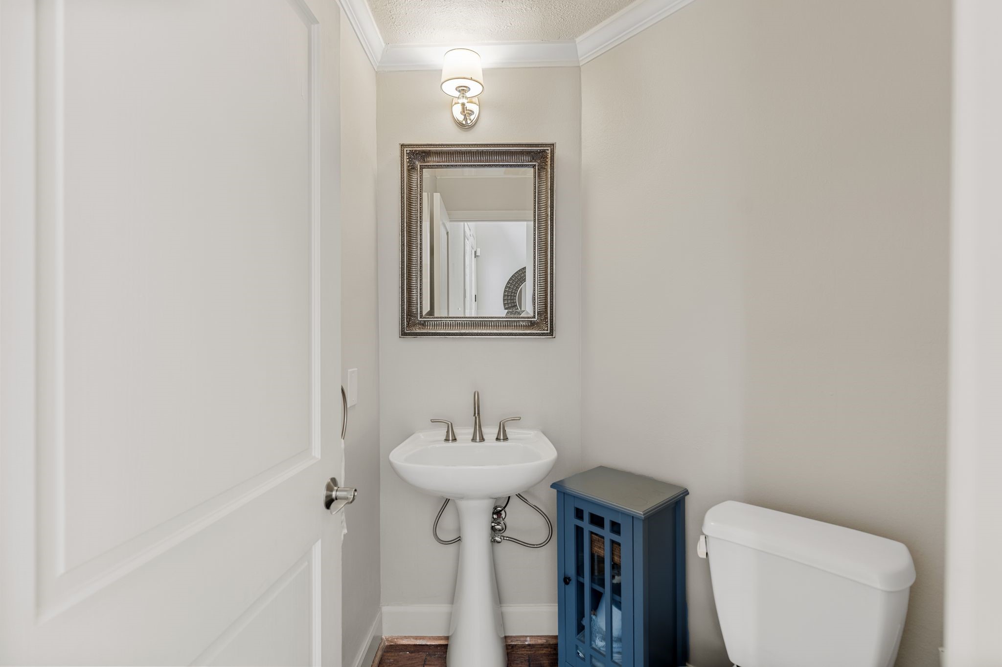The powder room features a classic pedestal sink, decorative framed mirror and wall sconce lighting.  It is discreetly located next to the mud room off entry.