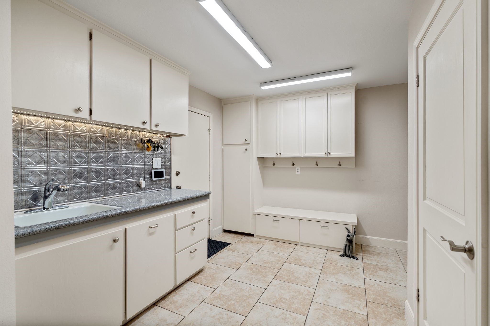 A spacious mud room offers a sink, extensive cabinetry and a built-in storage bench to help keep everyday essentials organized.
