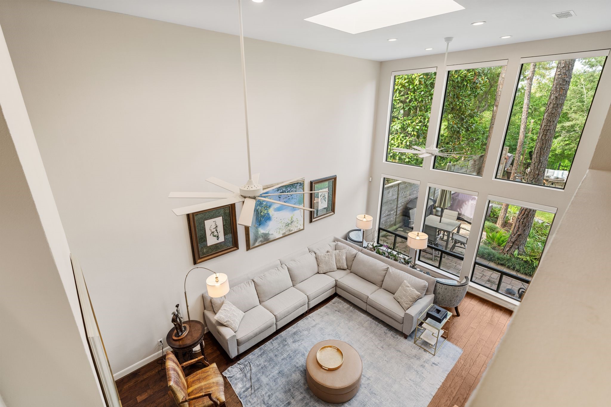The upstairs overlook showcases the living rooms dramatic two-story height, expansive windows and leafy views of the outdoor setting.