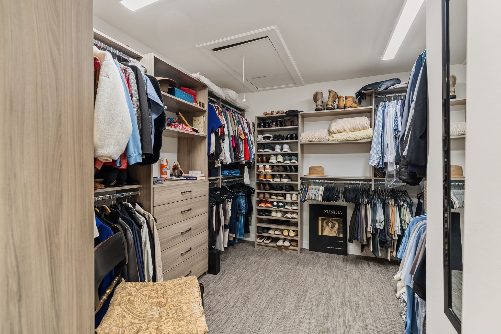A spacious walk-in closet features built-in drawers, extensive shoe shelving and multiple hanging sections for organized wardrobe storage.