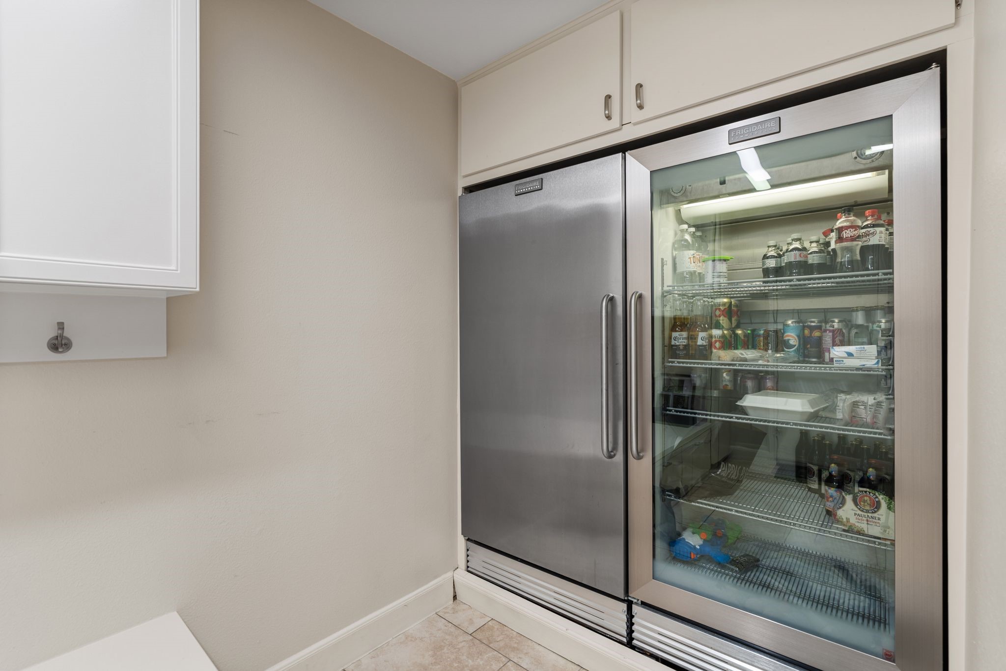 Also in the mud room, additional built-in refrigeration provides convenient storage for beverages and entertaining essentials, with overhead cabinetry adding useful storage space.