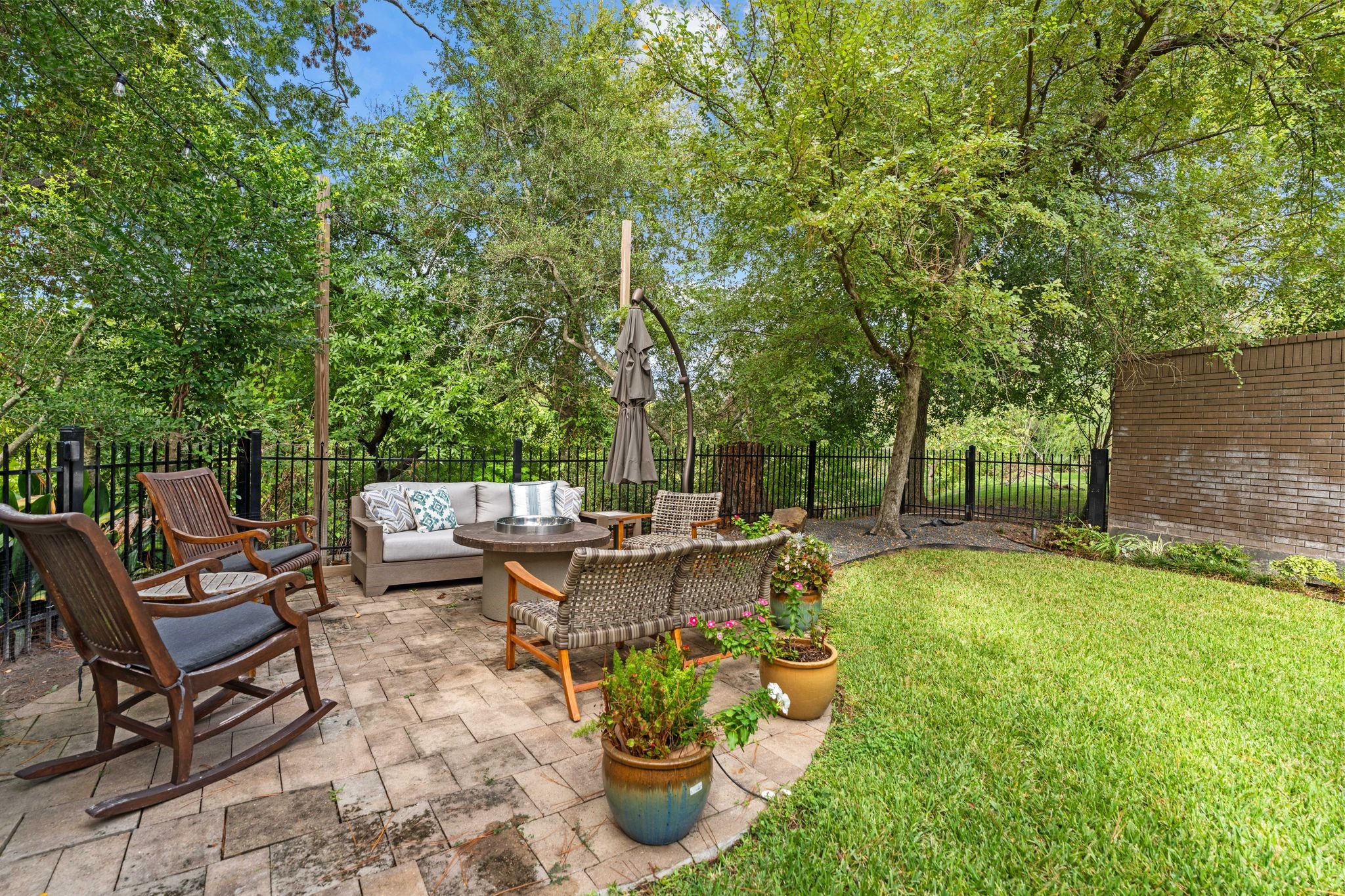 A garden sitting area surrounded by mature trees creates a peaceful spot for conversation and relaxation.