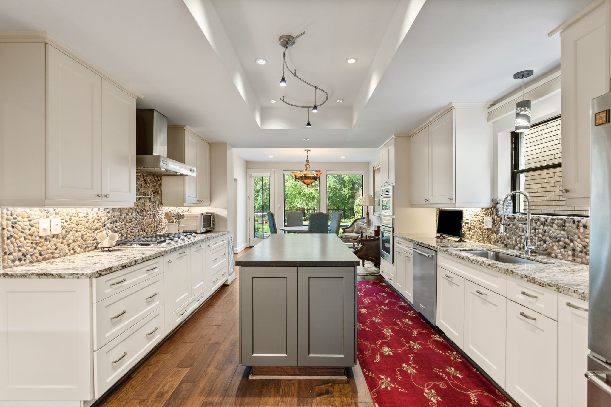 The spacious island kitchen combines abundant cabinetry, granite countertops and gas cooking, with a bright breakfast area overlooking the greenery beyond.