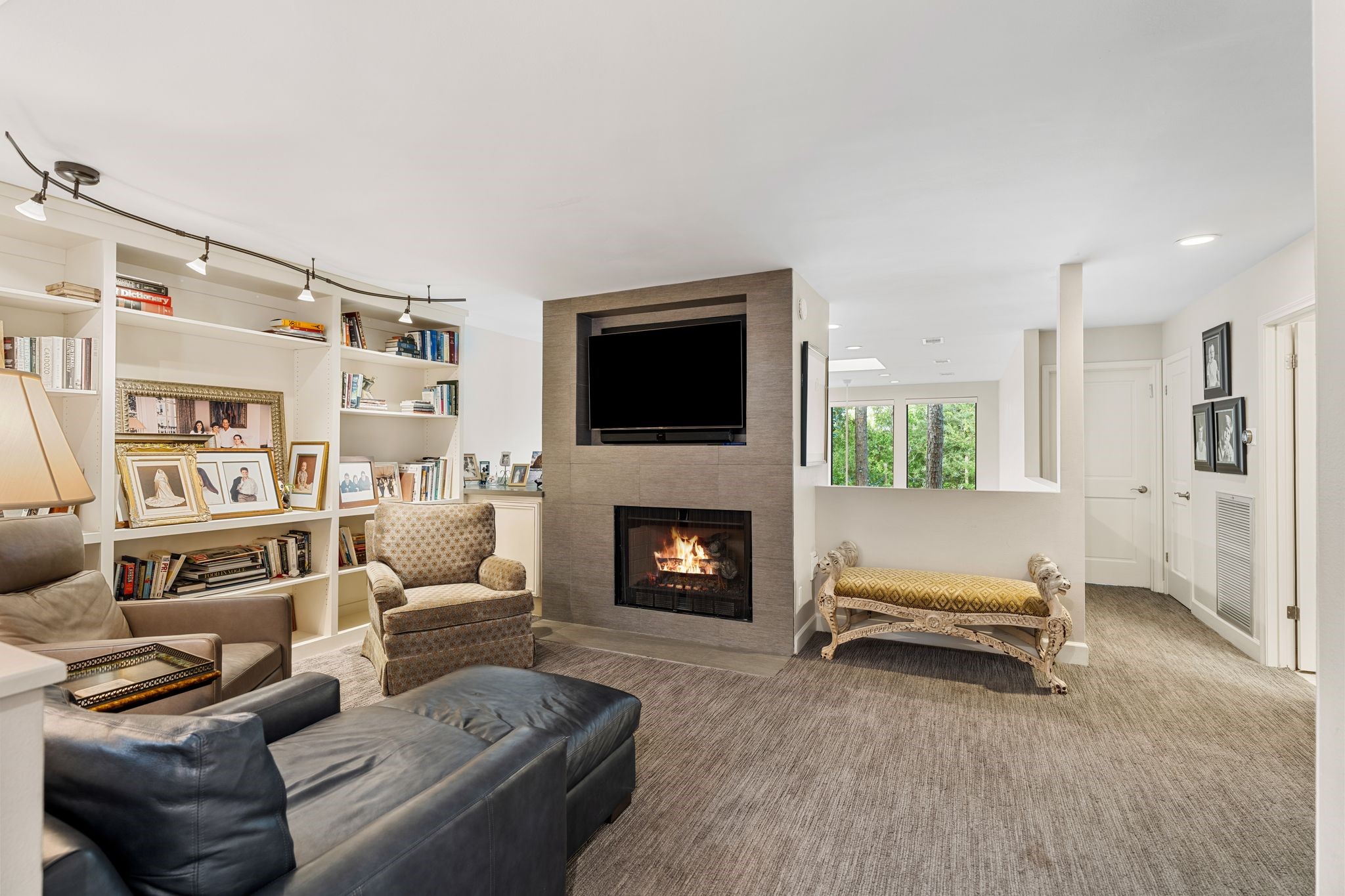 An upstairs den pairs a fireplace with a wall of built-in bookshelves, creating a comfortable retreat for reading, relaxing or movie nights.