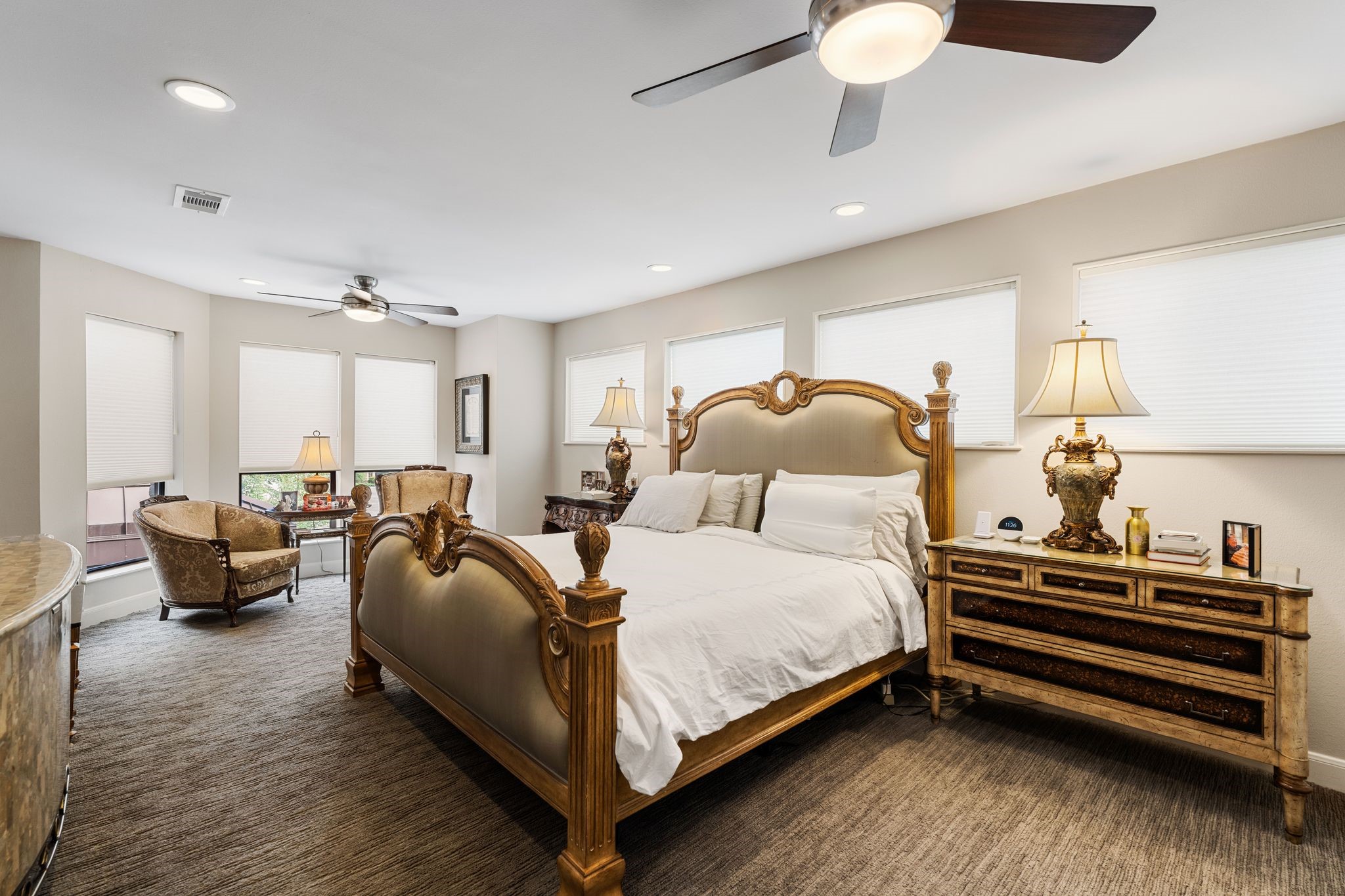 The primary bedroom extends into a windowed sitting area, providing ample room to unwind beyond the main sleeping space.