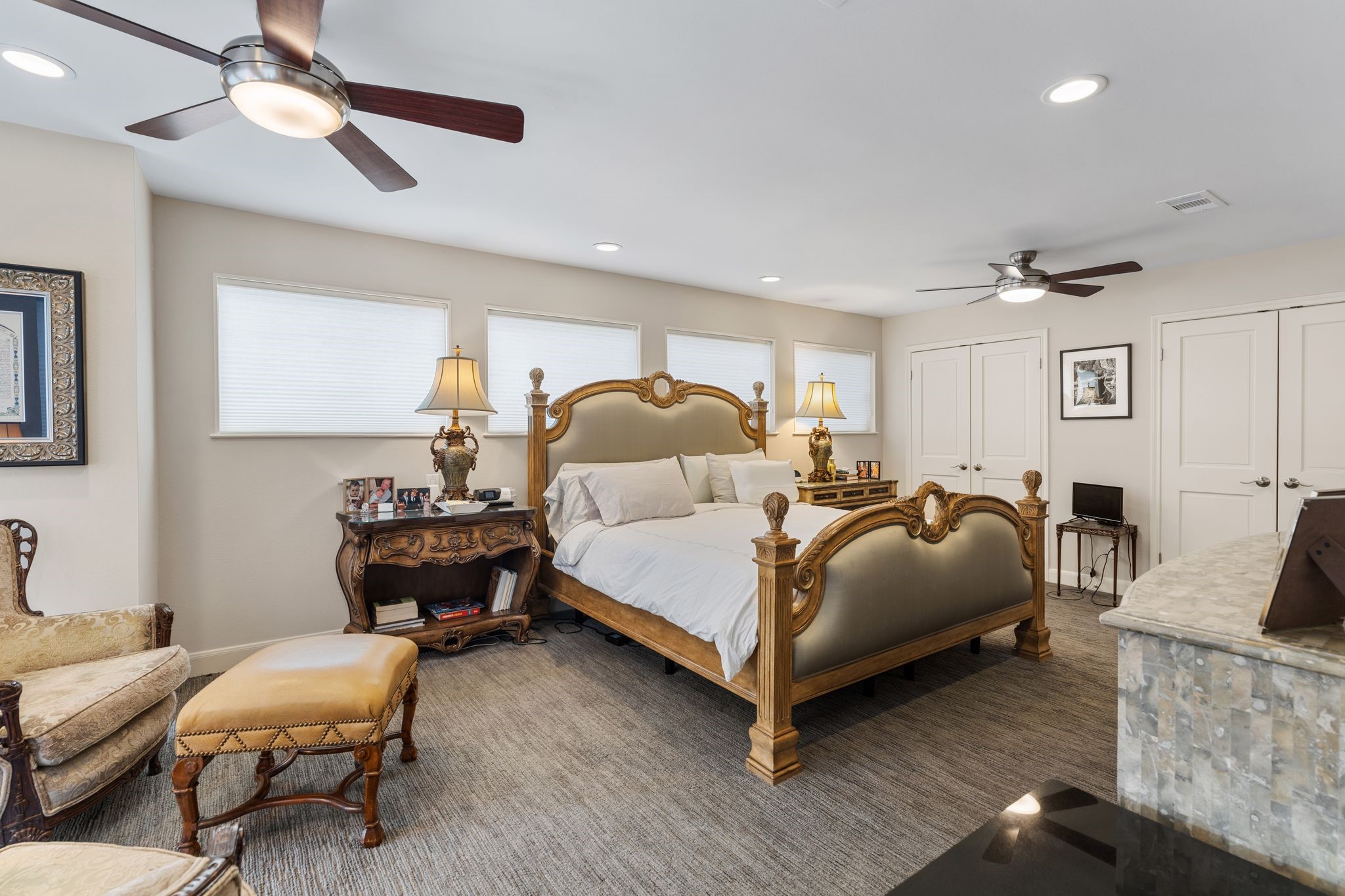 The spacious primary bedroom accommodates a substantial bedroom suite, complemented by multiple windows, recessed lighting and two ceiling fans.  Additional closet space is shown behind the two sets of doors.