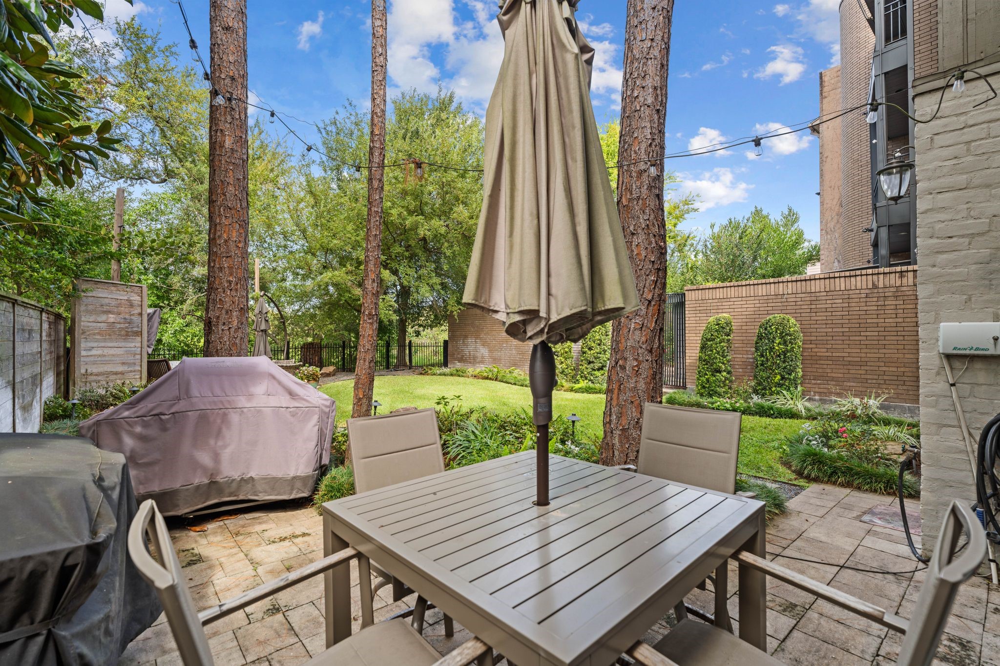 The patio beside the home provides an inviting setting for outdoor dining and grilling beneath mature trees.
