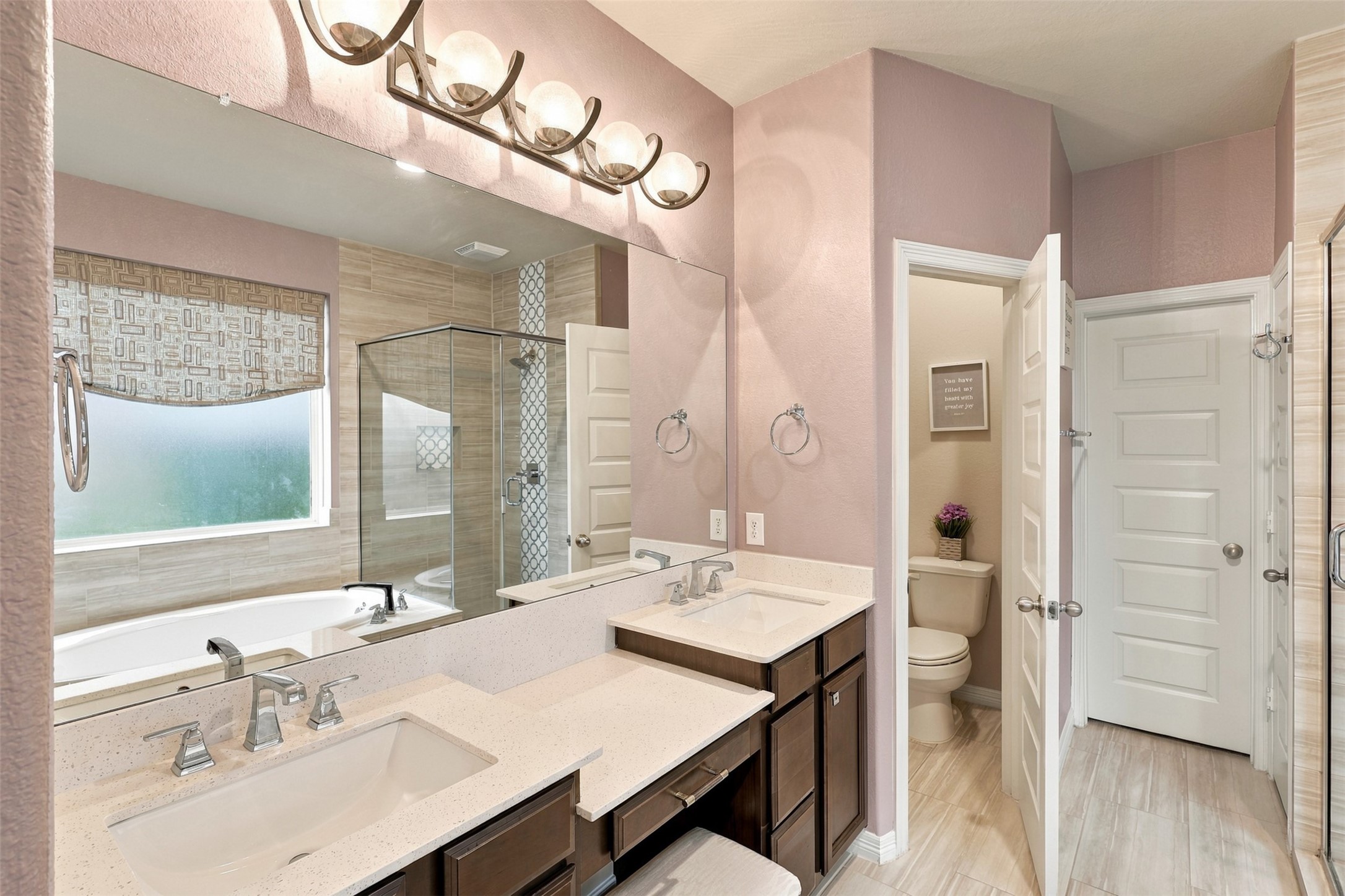 YOUR VERY OWN SPA-INSPIRED SANCTUARY! Step into this BEAUTIFUL primary bathroom, where everyday luxury meets timeless elegance! The impressive vanity features dual undermount sinks, expansive countertops, and abundant drawers to keep all your essentials beautifully organized! Gorgeous designer lighting adds a touch of sophistication, while a large window welcomes wonderful natural light, creating a bright and refreshing atmosphere!