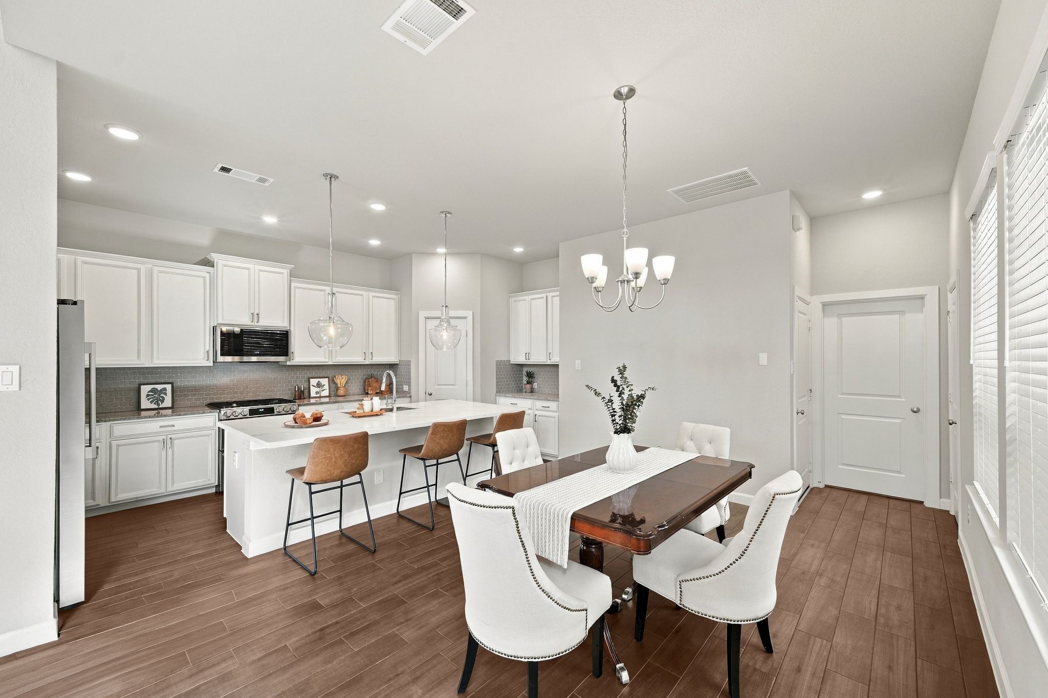 White cabinetry, a quartz island, and a dining table built for full house dinners. Every inch works together.